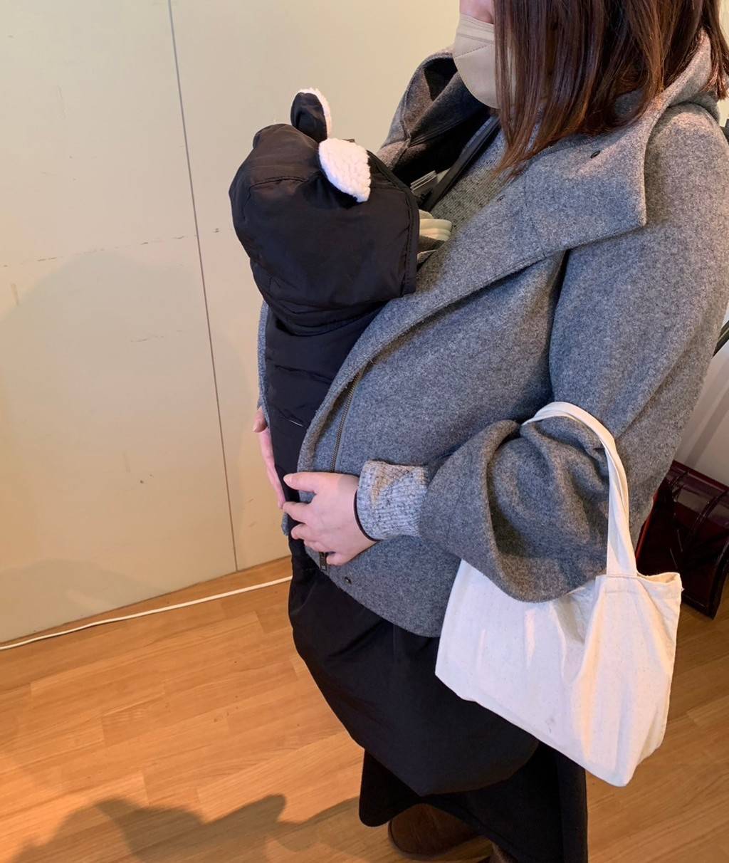 赤ちゃんを抱っこ紐ケープで抱っこする女性