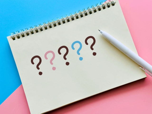 ピンクと水色背景でクエスチョンマークが書かれたスケッチブックとペンがある