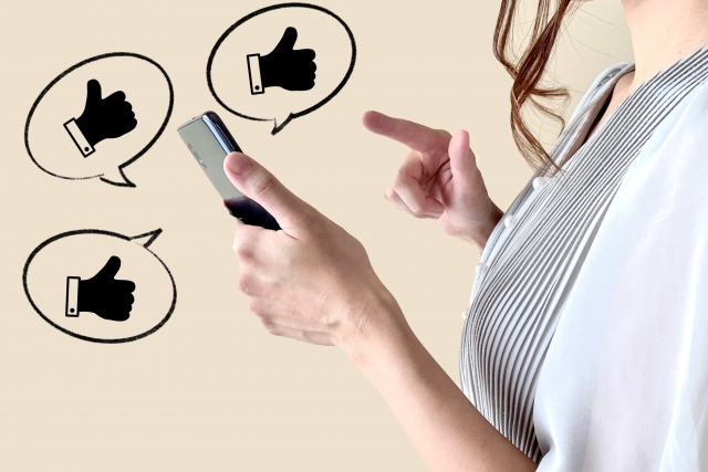 スマホでSNSの口コミをチェックしている女性