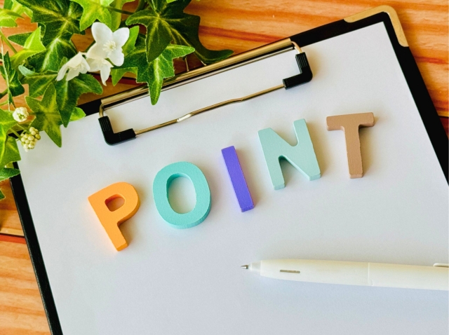 机の上にPOINTの文字が書かれたバインダーとペン