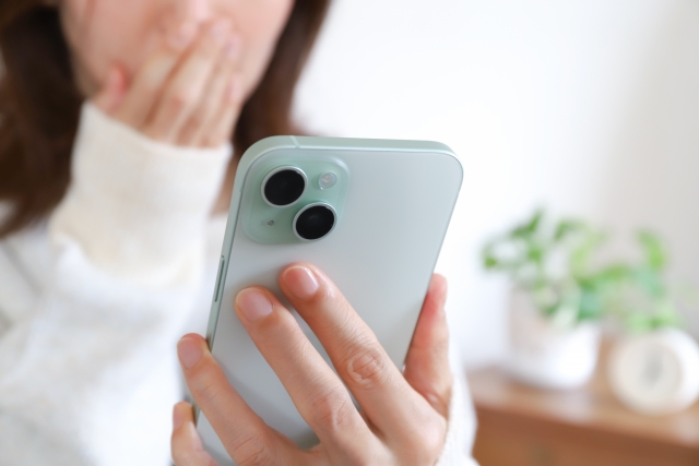 スマホを見て驚く女性